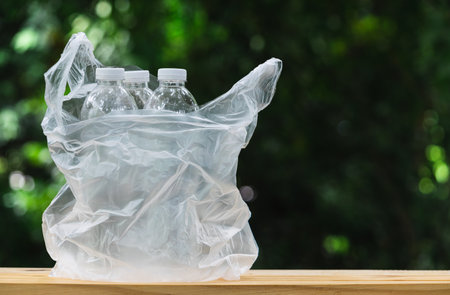 Plastic bottle in plastic bag on wooden in nature background. global warming concept.の写真素材