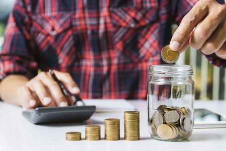 Men are Saint documents about save money and put coin in glass jar also have  calculator, coins on...