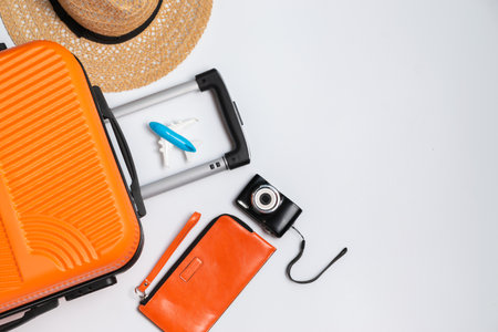 Flat lay orange suitcase with traveler accessories on white background. travel, summer and holiday conceptの写真素材