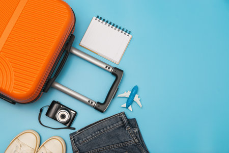 Flat lay orange suitcase with traveler accessories on soft blue background. travel, summer and holiday conceptの写真素材