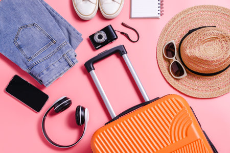 Flat lay orange suitcase with traveler accessories on soft pink background. travel, summer and holiday conceptの写真素材