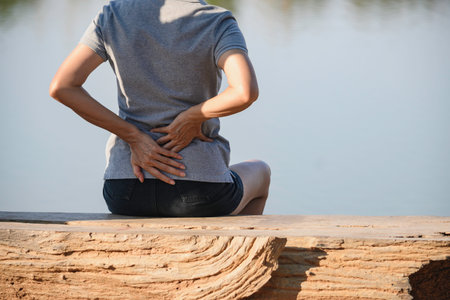 Closeup hands of woman touching her back pain in healthy concept on nature background.