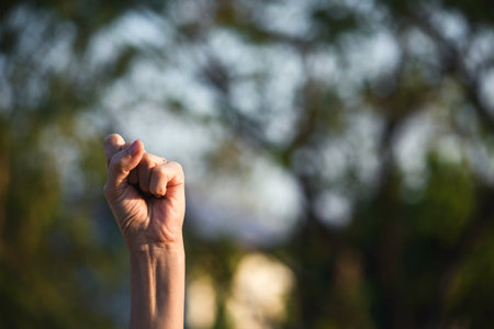 Hand up fist of female in garden green nature  background for,teamwork concept.の写真素材