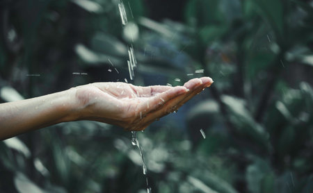 Closeup water flow to hand of women for nature concept on the garden background.の写真素材