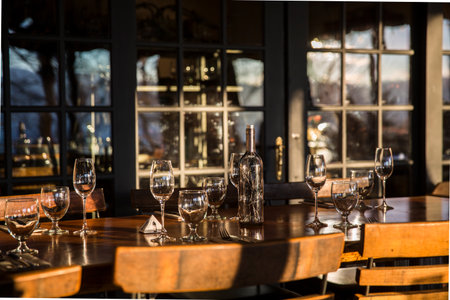 Restaurant table setting with empty wine glasses and wine bottles.
