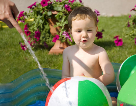 Toddler playing with water in the hot dayの写真素材