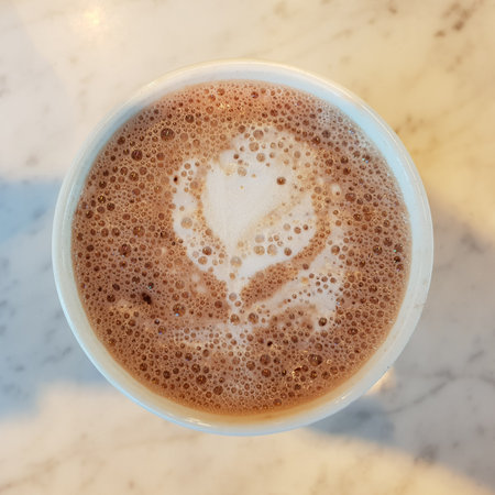 Top down view of a mug with hot chocolate and latte art placed on white marble tableの写真素材