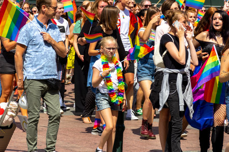 MalmÃ¶, Sweden - July 20 2019: A young girl in glasses with a sceptical look waves her rainbow colored pride flag while attending the 2019 pride parade through the streets of downtown MalmÃ¶, Sweden.のeditorial素材