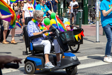 MalmÃ¶, Sweden - July 20, 2019: A senior woman on a mobility scooter, decorated with rainbow flags and colors, is participating in the annual pride parade in MalmÃ¶, Sweden.のeditorial素材