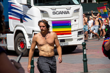 MalmÃ¶, Sweden - July 20, 2019: A bare chested man is walking in front of a Scania truck as they both participate in the annual gay pride parade in MalmÃ¶, Sweden.のeditorial素材