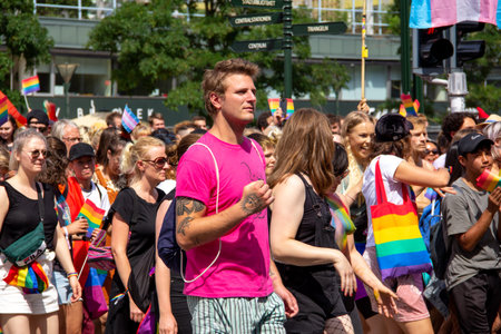 MalmÃ¶, Sweden - July 20, 2019: A young adult man with tattoos in a pink shirt is pumping his fist as he is parading with other people in the annual gay pride parade in downtown MalmÃ¶, Sweden.のeditorial素材