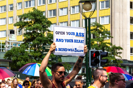 MalmÃ¶, Sweden - July 20, 2019: A young scruffy looking man in sunglasses holding a sign with the text "Open your ass and you heart and mind will follow", as he is parading in the gay pride parade.のeditorial素材