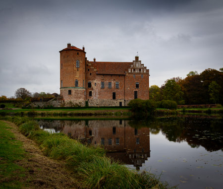 Torup, Sweden - October 20, 2019: The tower and the brick facade with old windows are visible as well as the reflection of the castle in the lake next to itのeditorial素材