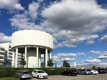 Lund, Sweden - July 23, 2017: Some cars parked on the parking lot next to the water tower on a calm summer day with fluffy clouds and blue skyのeditorial素材