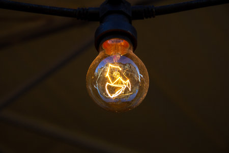 A single electric light bulb lit hanging from the ceilingの写真素材