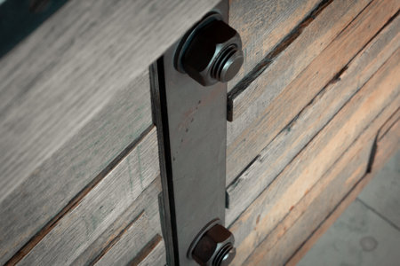 A piece of metal fastened with screews and bolts on a wooden weathered panelの写真素材