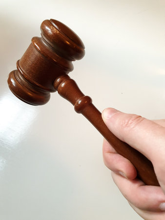 Male hand holding a wooden gavel on white backgroundの写真素材