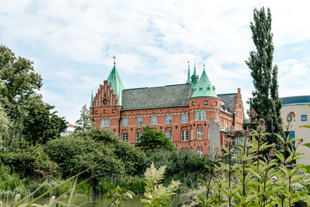 MalmÃ¶, Sweden - July 19, 2019: The old castle like building is housing the city library. It stands in the middle of a green park called Slottsparken and Kungsparkenのeditorial素材