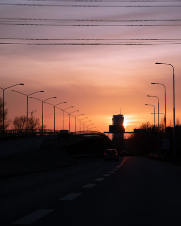 Driving on the highway towards a skyscraper with the sun setting behind it in MalmÃ¶, Swedenの写真素材