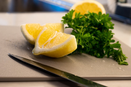 Parsley and freshly cut lemon slices on a cutting board with knifeの写真素材