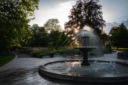 The sunlight comes through a tree during sunset hitting the fountain in the park Stadsparken in Lund, Swedenの写真素材