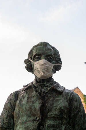 Lund, Sweden - June 24, 2020: Someone placed a white face mask on a male statue as a reference to that people should wear facemasks to avoid getting sick by Covid-19 in Swedenのeditorial素材