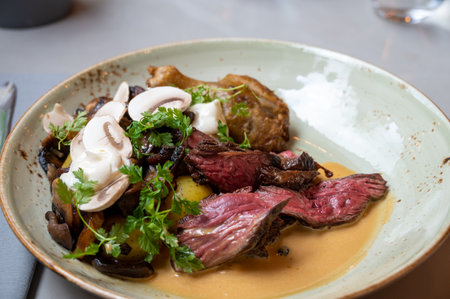 A meal based around butchers steak with mushrooms and tomatoes served in a gray rustic plate in restaurant settingの写真素材