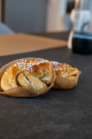 Fresh cinnamon buns with sugar on top placed on a dark rustic stone tableの写真素材