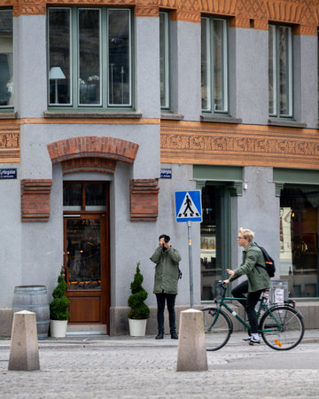 Lund, Sweden - October 10, 2020: Young man photographing in front of medieval building while university student cycles byのeditorial素材