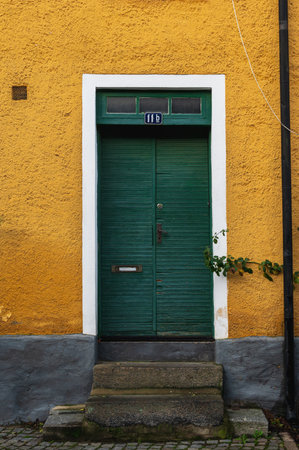 A rough green door in a yellow building in Lund Swedenの写真素材