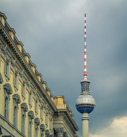 Berlin TV tower next to old building facade with cloudy gray skyのeditorial素材