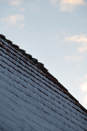 Snow covered tiled roof in minimalistic style against winter skyの写真素材