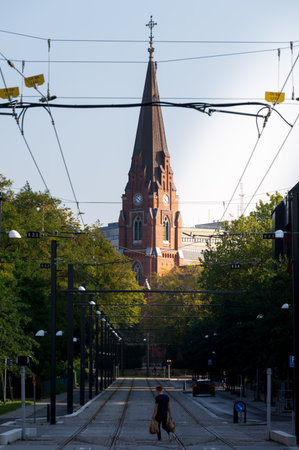 A man crossing the tramway in front of the church Allhelgonakyrkan in Lund Swedenの写真素材