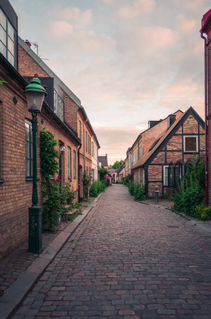 Narrow cobblestoned alley with half-timbered house in old town Lund Sweden during summer sunsetの写真素材