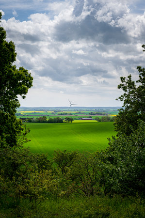 Dramatic clouds over green flat farmlands with wind turbine in SkÃ¥ne Swedenの写真素材
