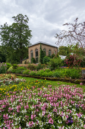 Fields of colorful flowers in front of old green house in Lund Botanical Gardens in Swedenのeditorial素材