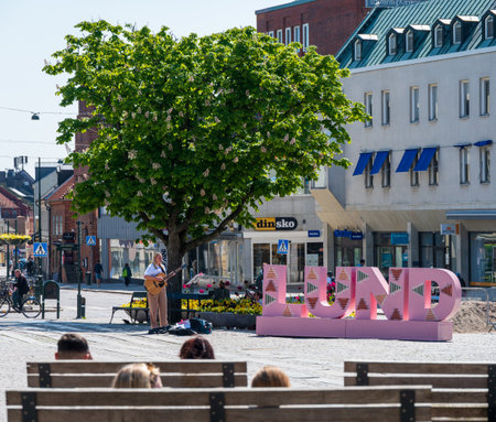 Lund, Sweden - May 30 2021: A young woman playing the guitar and singing on town square during pandemicのeditorial素材