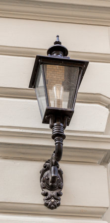 Electric old fashioned lamp light mounted on historic facadeの写真素材