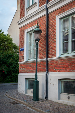 Historic old electric lamp on cobblestoned street next to brick facade in Lund Swedenの写真素材