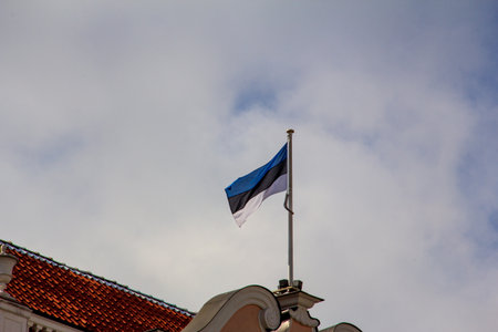 The Estonian flag mounted on a flag pole on a roof in Tallinn Estoniaの写真素材