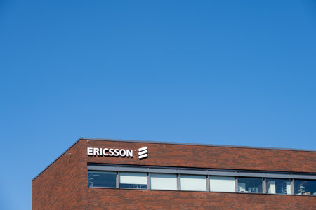 Lund, Sweden - April 22 2022: The logo of Ericsson mounted on the brown brick facade against blue skiesのeditorial素材