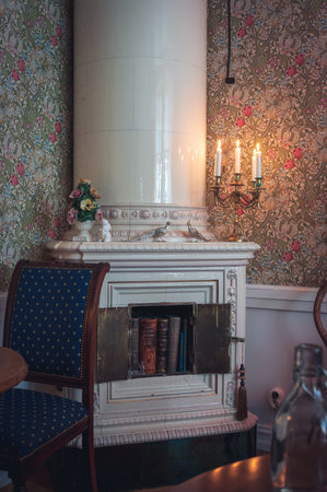 Masonry heater decorated with candelabra and books in the corner of a historic roomの写真素材