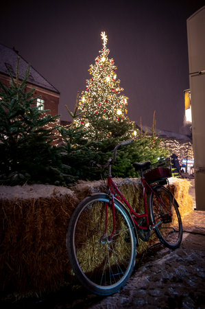 Bicycle parked next to a place where they sell christmas trees with a huge decorated tree in the background in the city center of Lund Swedenの写真素材