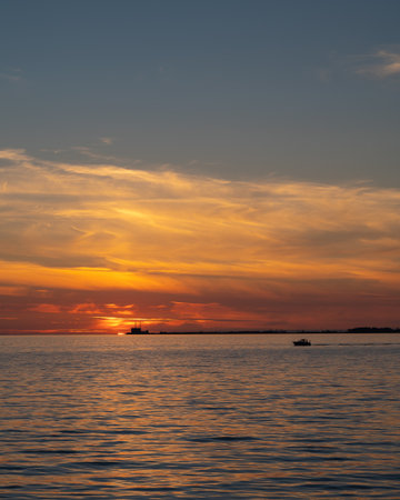 Burning sunset over the sea Ãresund outside Sweden with nuclear power plant BarsebÃ¤ck on the horizonの写真素材