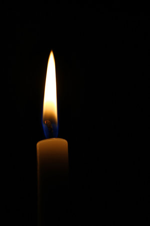 Candle burning on black background
