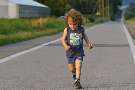 Young child running on a long country roadの写真素材