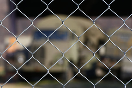 Old military transport truck as a background behind a chain link fence at an army depotの写真素材