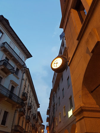 Old european street with illuminated wall clock at night