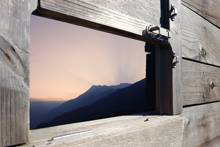 Sunrise over the Alps in Switzerland framed through a wooden shelterの写真素材