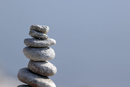 Column of hand piled granite rocks against blue water backgroundの写真素材